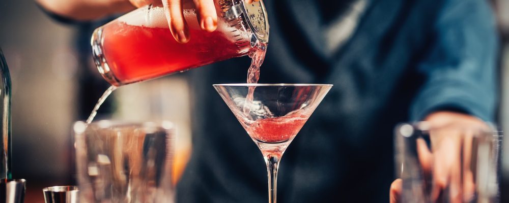 Close up details of barman pouring vodka cosmopolitan cocktail in martini glass Close up details of barman pouring vodka cosmopolitan cocktail in martini glass