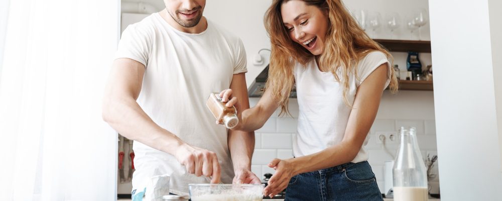 Image of gorgeous couple cooking and mixing dough in kitchen at home Image of gorgeous couple cooking and mixing dough in kitchen at home